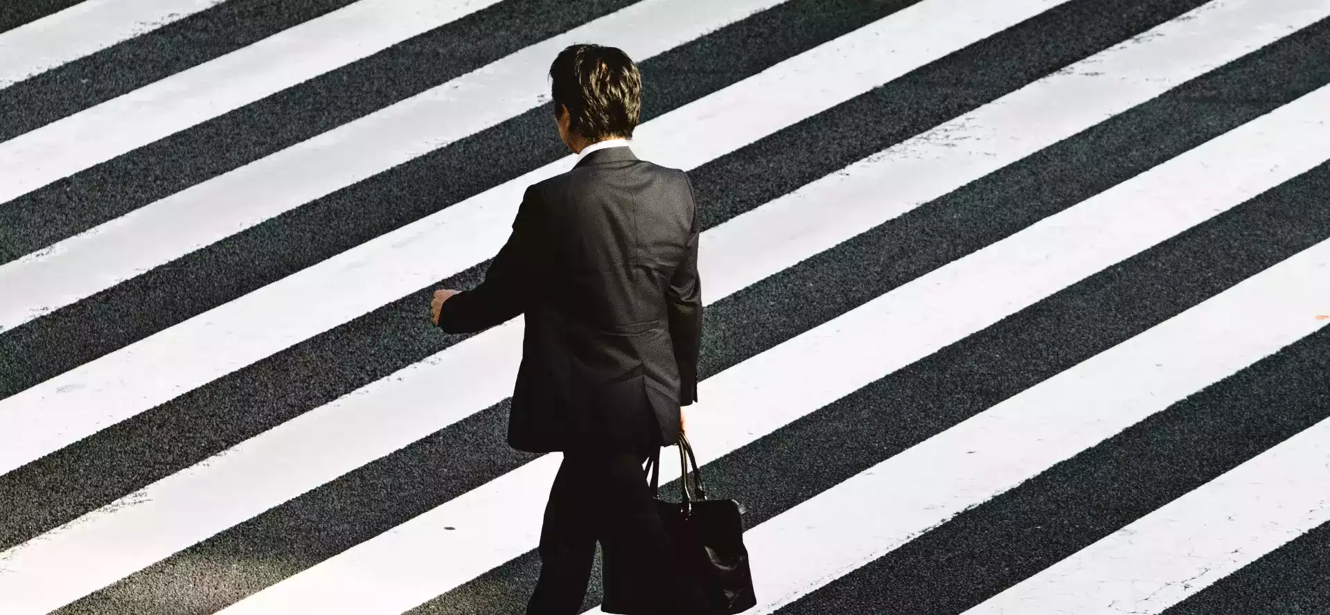Photographie d'un homme d'affaire qui traverse un passage piéton